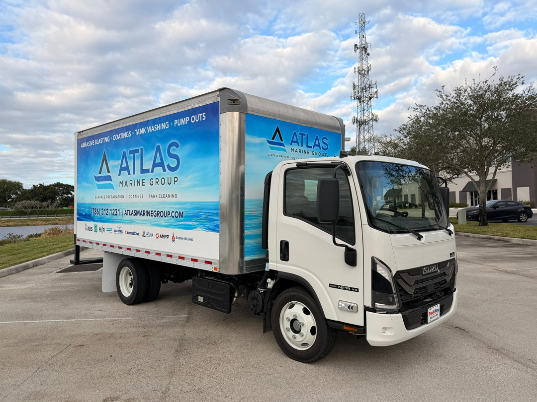 White Isuzu delivery truck with a large blue Atlas Marine Group trailer parked in a lot; ad includes contact info and services like coating and tank washing.