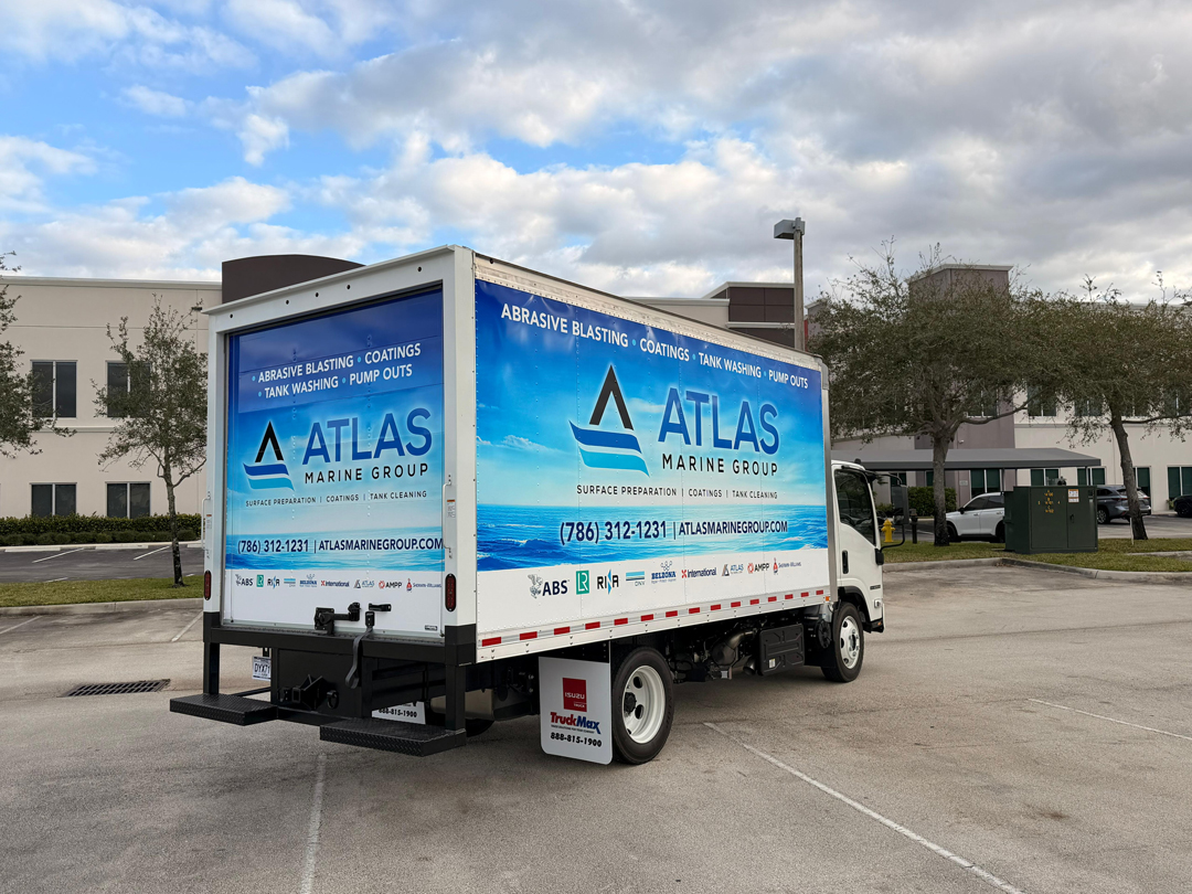 Blue Atlas Marine Group delivery truck parked in a lot with company branding on the sides and contact info visible on the wrap.