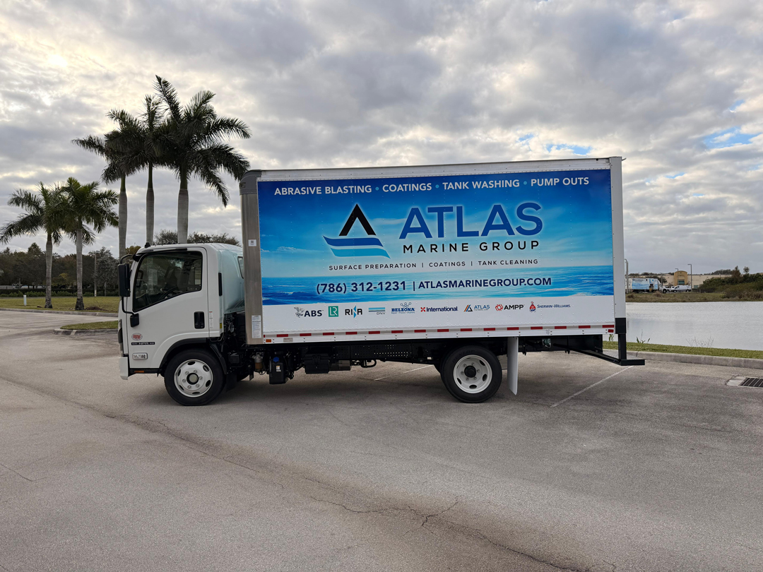 Box truck with Atlas Marine Group branding and blue ocean graphic parked near palm trees, advertising services like abrasive blasting and tank cleaning.