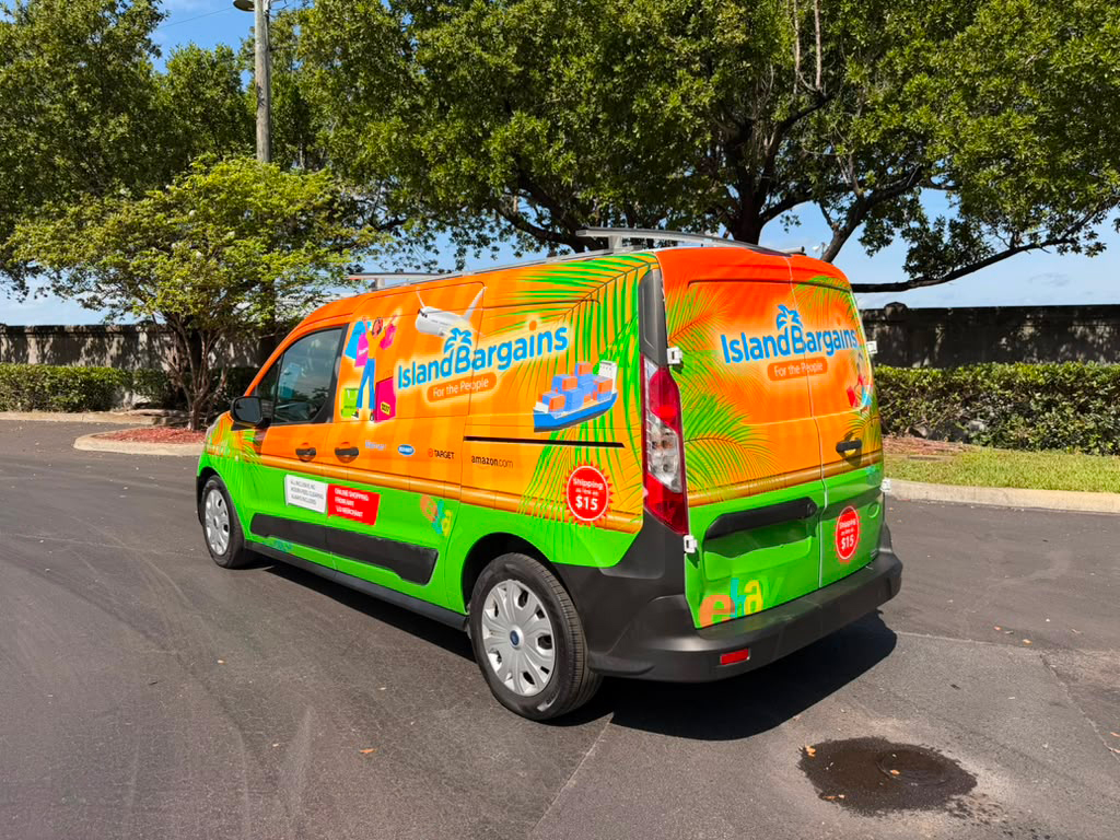 Bright orange and green delivery van with Island Bargains branding parked in a lot; tropical graphics and logos visible on sides and rear.