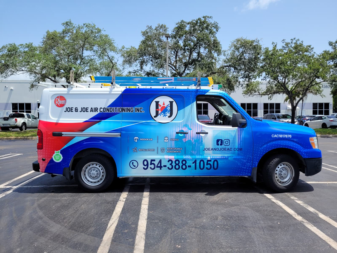 Blue and red service van for Joe & Joe Air Conditioning with ladders on top and contact number 954-388-1050 visible in a parking lot