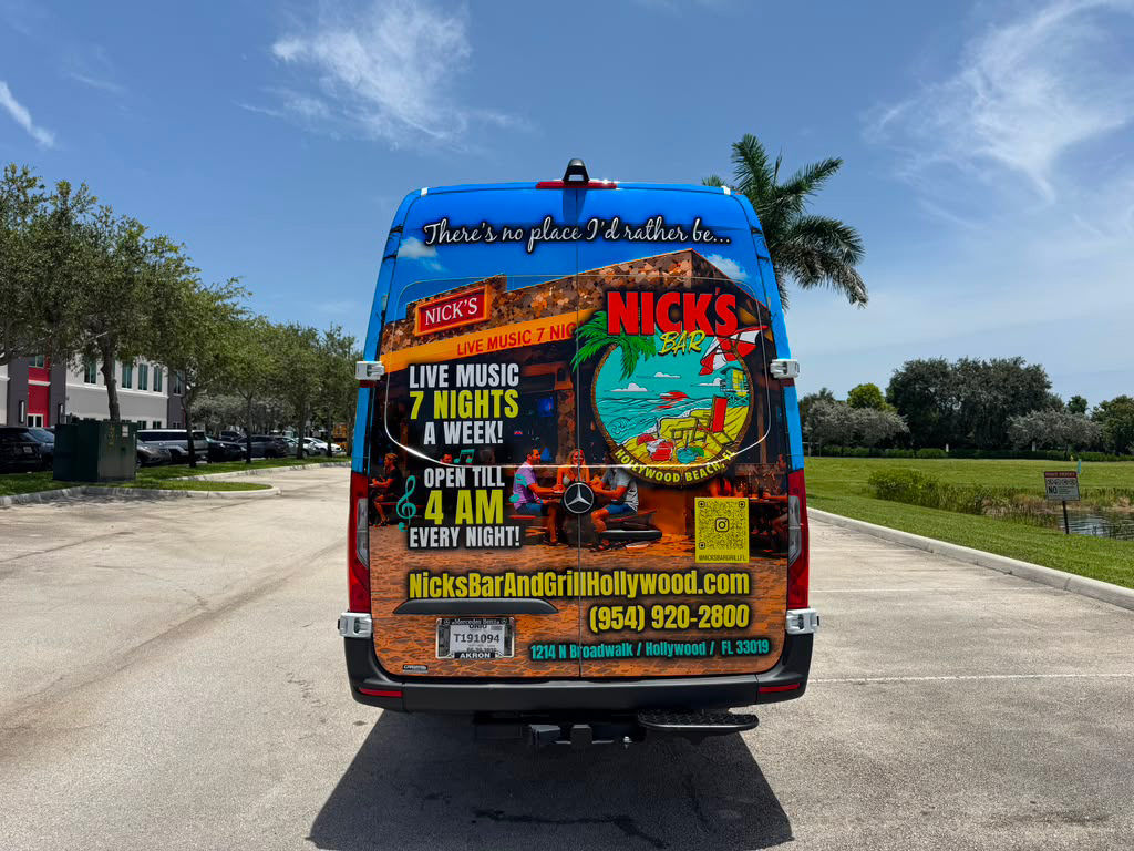 Rear view of a blue promotional van for Nick's Bar & Grill Hollywood, with tropical graphics and text advertising live music seven nights a week and late hours, plus the website and phone number.