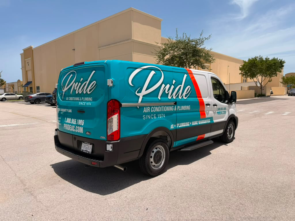 Rear and side view of a turquoise Pride air conditioning and plumbing van parked in a sunny lot beside a beige commercial building.