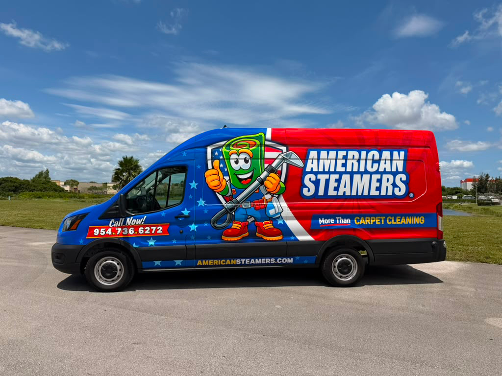 Blue and red carpet-cleaning van featuring a cartoon mascot giving a thumbs-up and the 'AMERICAN STEAMERS' branding on the side.