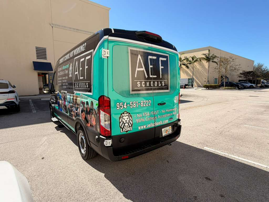 Teal AEF Schools van parked in a lot, showing the rear with the AEF logo and contact info.