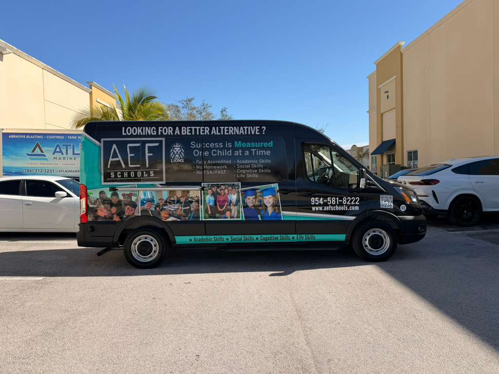 Black promotional van parked in a lot advertising AEF Schools, with a collage of student photos and the contact number 954-581-8222 on the side panel.