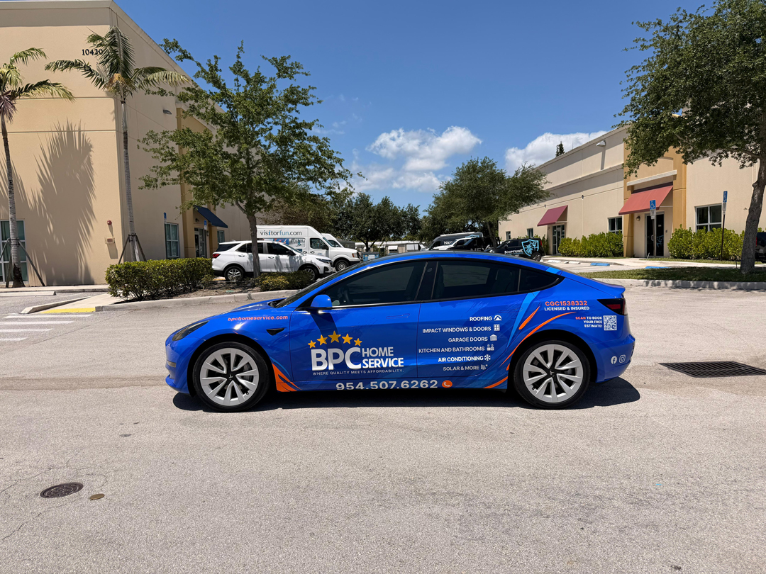 Blue BPC Home Service promotional car with service list on the side, parked in a sunny parking lot near beige commercial buildings.