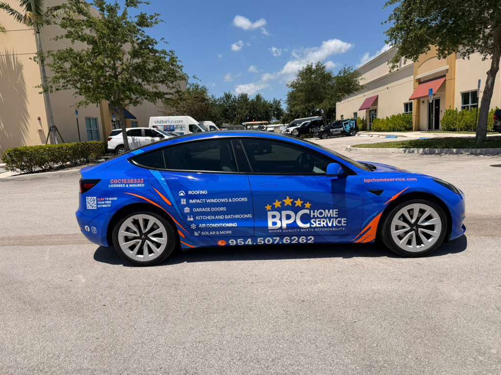 Blue promotional car for BPC Home Service parked in a shopping plaza lot, with service details on the side panel.